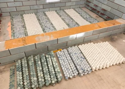 Rows of circular tiles, blue and white, laid on a floor next to a partially tiled wall.