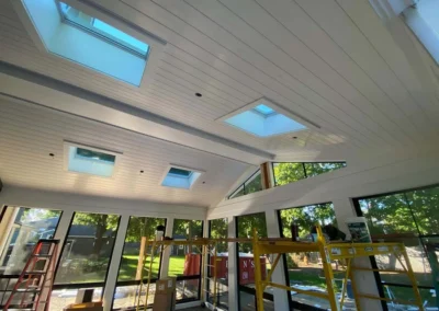 Interior view of a bright, modern room with large windows, skylights, and custom carpentry.