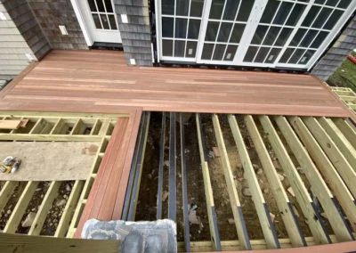 Partially constructed outdoor wooden deck with visible wooden framework and completed decking area in front of a house.