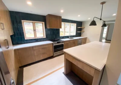 Modern kitchen with wooden cabinets, dark backsplash, island, and pendant lights.