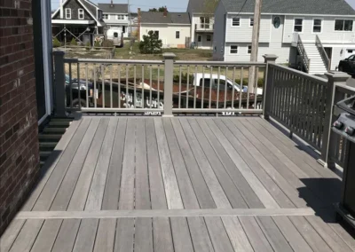 A newly constructed wooden deck with railing overlooking a residential neighborhood.