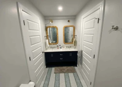Modern bathroom with dual mirrors, a navy blue vanity, and striped tile floor.