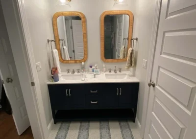Modern bathroom with dual sinks, wooden mirrors, and mosaic tile floor.