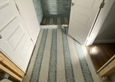 Bathroom with mosaic tile floor and subway tile shower wall.