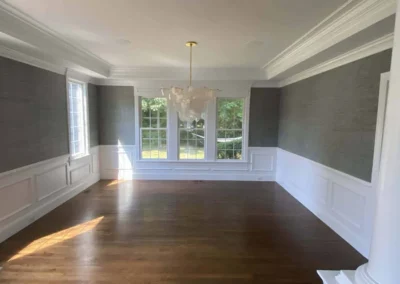 Elegant dining room with wooden floor, white wainscoting, and large windows.