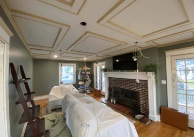 Living room with coffered ceiling, fireplace, and covered furniture.