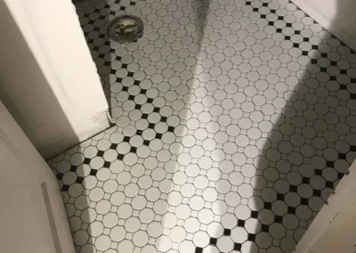 White hexagonal tile floor with black accents in a small room, partially unfinished walls.