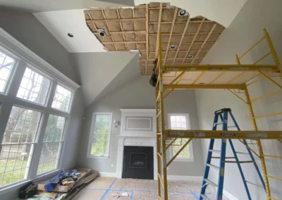 Living room under renovation with scaffolding and exposed ceiling.