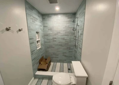 Modern bathroom with blue tiled walk-in shower and toilet.
