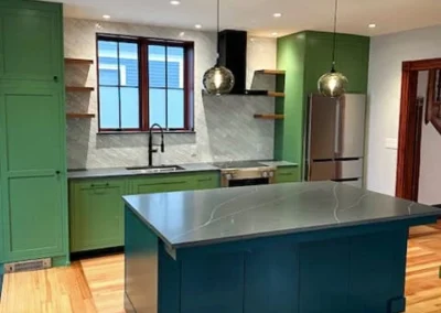 Modern kitchen with a blue island, green cabinets, and stainless steel appliances.