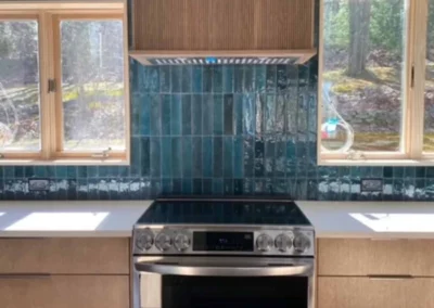 Modern kitchen with custom wooden cabinetry and teal tile backsplash.